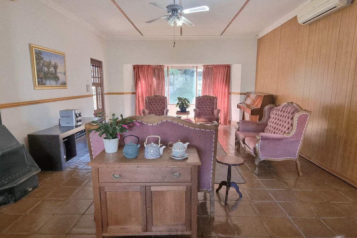 Spacious living room featuring a freestanding fireplace, timber wall paneling, tiled flooring, and a split-system air conditioner.