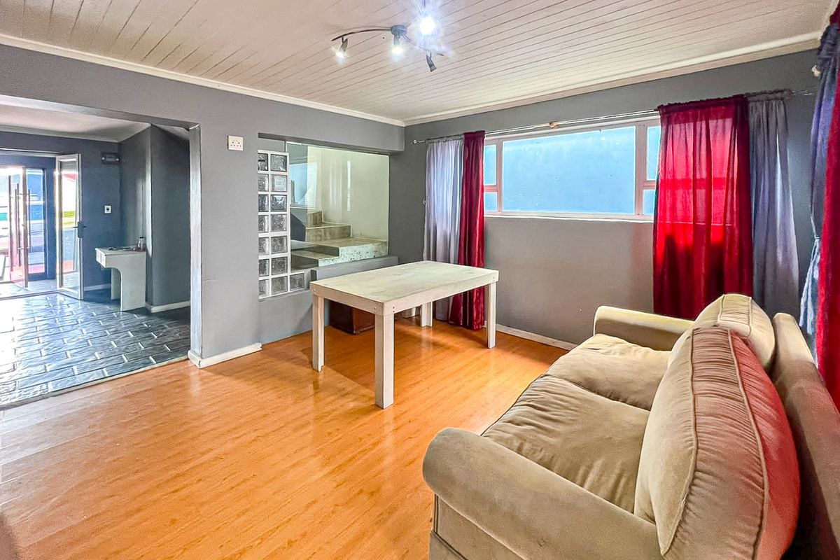 Living room featuring laminate flooring, a unique glass block partition, and timber ceiling, providing a functional space with potential for modern updates.