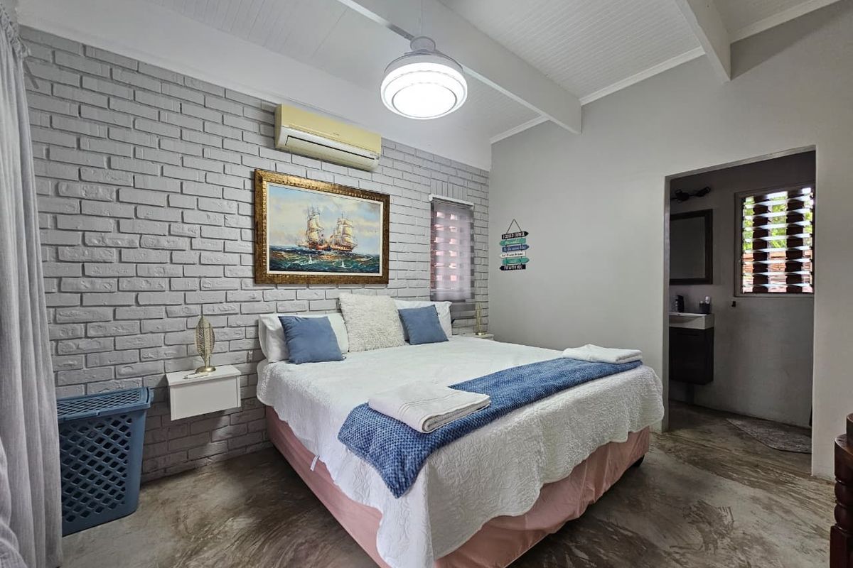 A bedroom featuring a painted brick accent wall, polished concrete flooring, and an en-suite bathroom entrance.