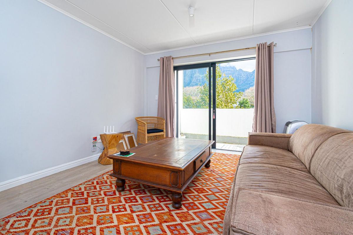 A bright living room featuring laminate flooring and large sliding glass doors that open onto a balcony with scenic mountain views.