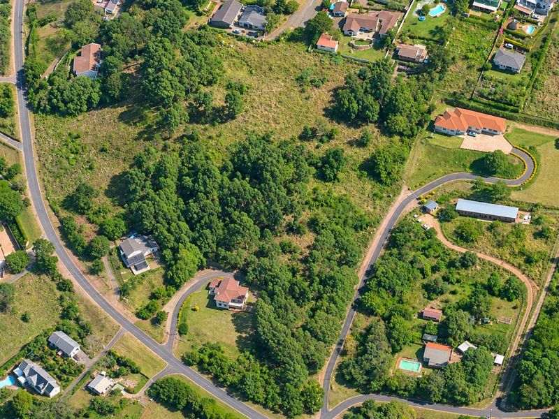 An aerial view of a residential area featuring established plots, mature trees, and surrounding road infrastructure in a quiet neighborhood setting.