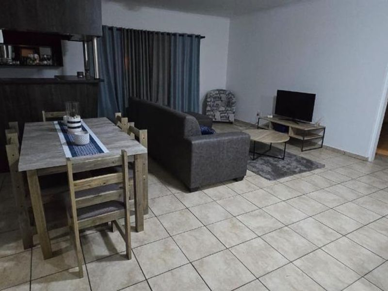 Open-plan living and dining area featuring tiled flooring and a breakfast bar, providing a functional layout for daily living.