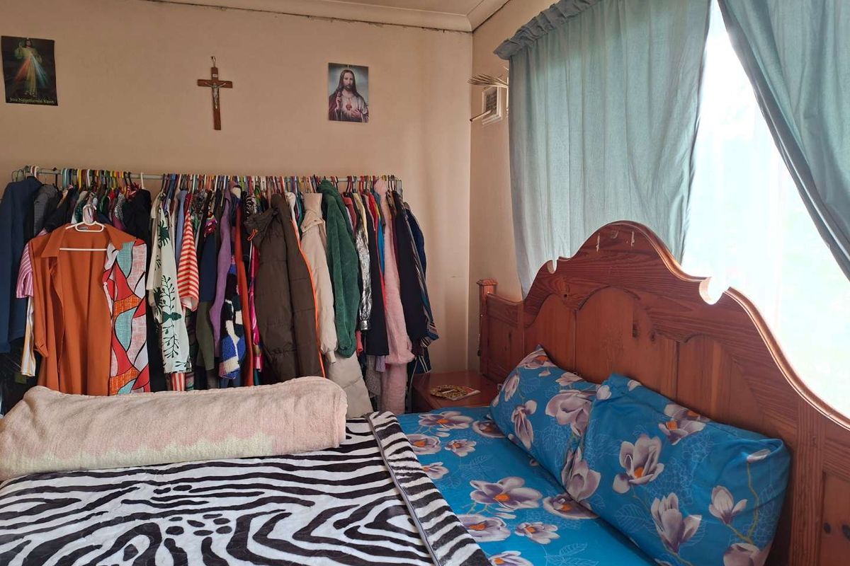 A bedroom featuring a window with curtains and visible signs of wear on the ceiling and walls, offering potential for cosmetic renovation.