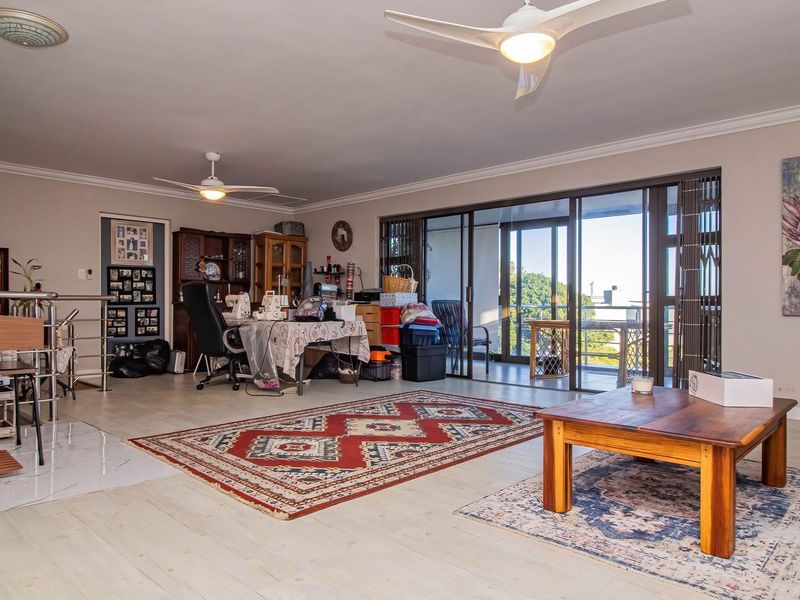 Spacious living area featuring tiled flooring, ceiling fans, and large sliding glass doors that provide access to an outdoor balcony area.