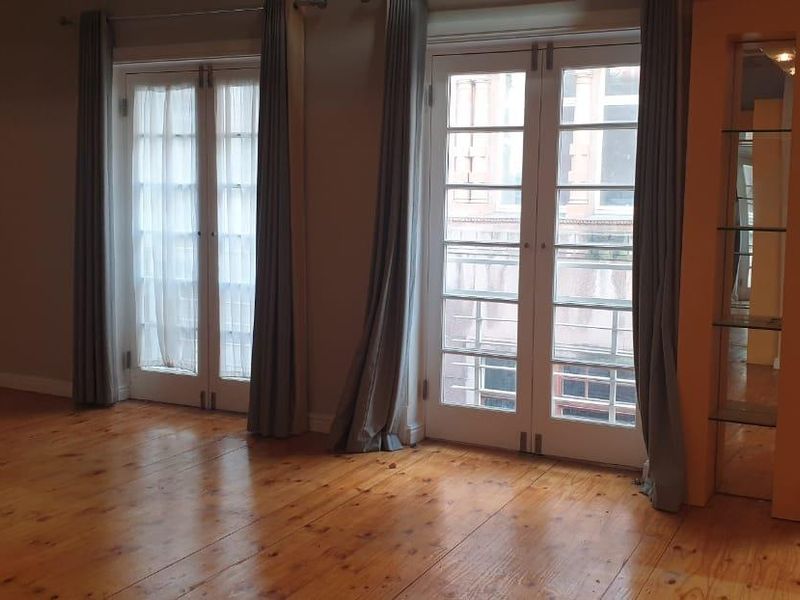 A bright living area featuring polished timber flooring and multiple sets of French doors providing access to the exterior.