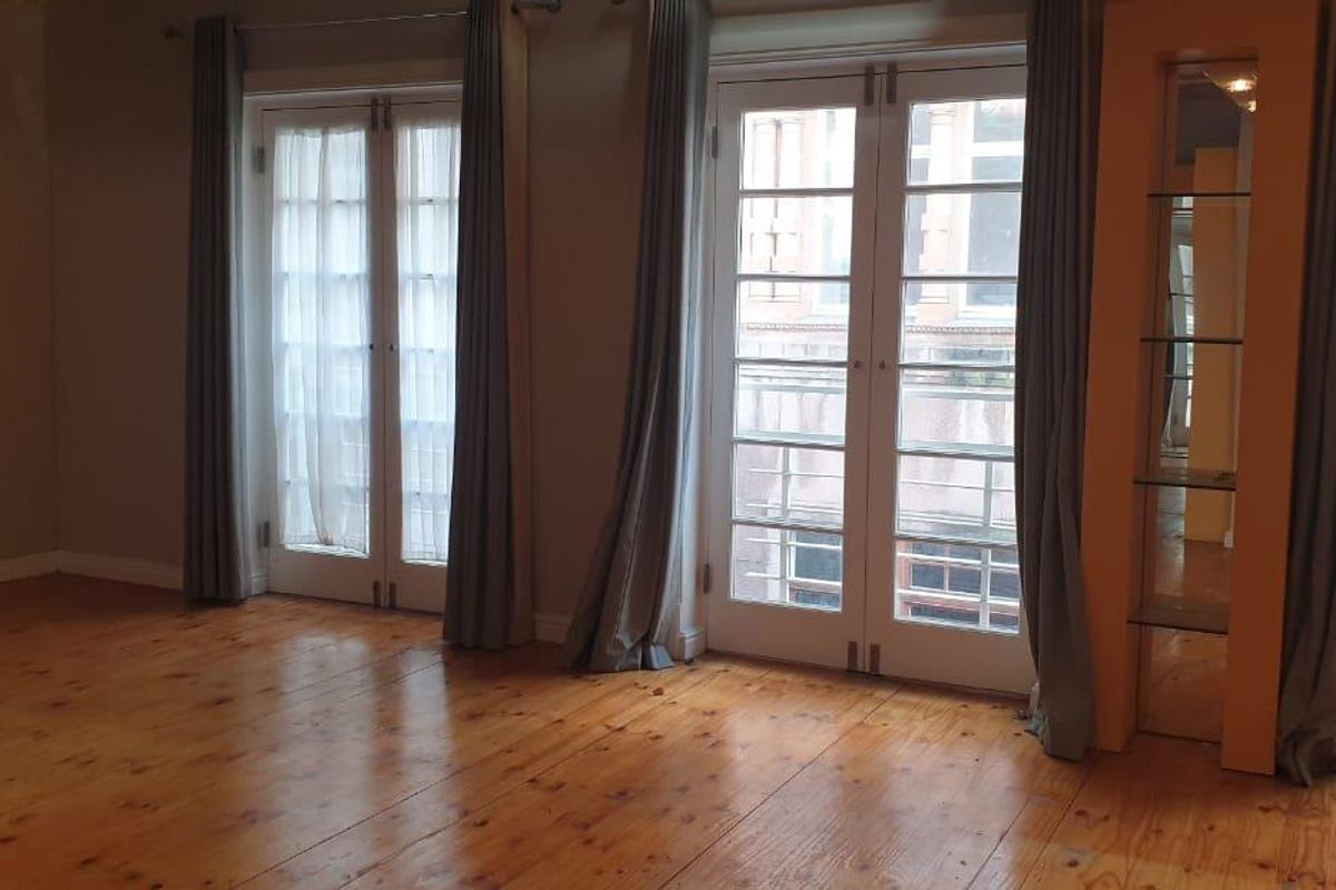 A bright living area featuring polished timber flooring and multiple sets of French doors providing access to the exterior.