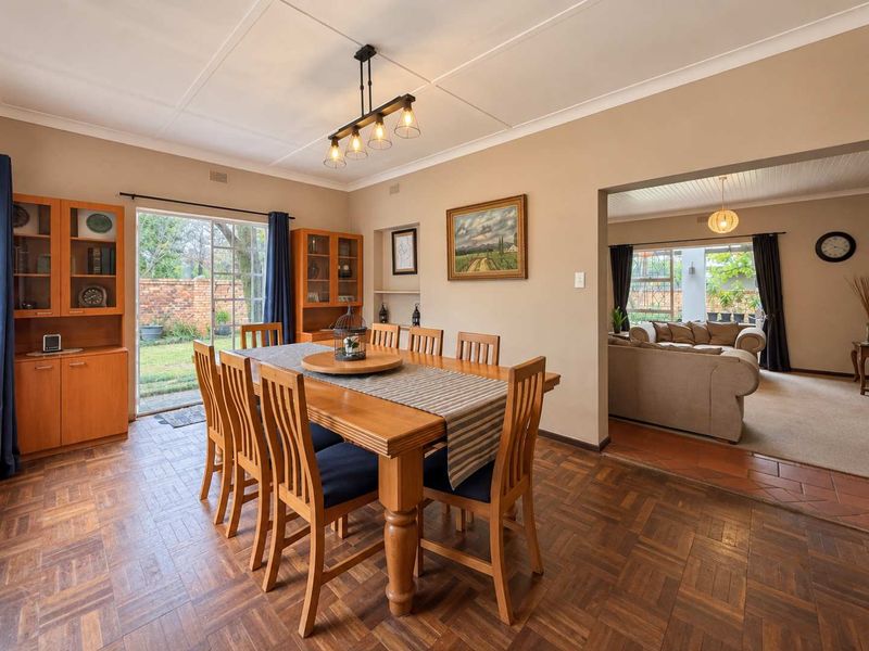 Spacious dining room featuring classic parquet flooring, built-in cabinetry, and a sliding glass door providing direct access to the rear garden.