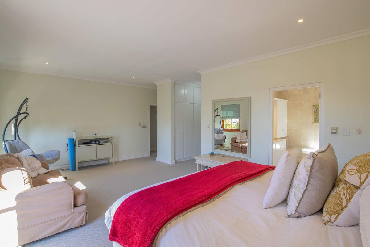 Spacious bedroom featuring neutral carpeting, built-in cabinetry, and an en-suite bathroom with tiled finishes.