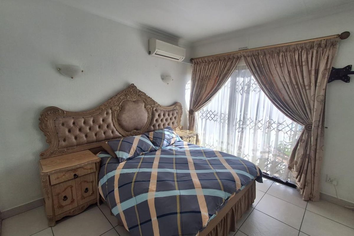 A bedroom featuring tiled flooring, a wall-mounted air conditioning unit, and sliding glass doors with security gates leading to the exterior.