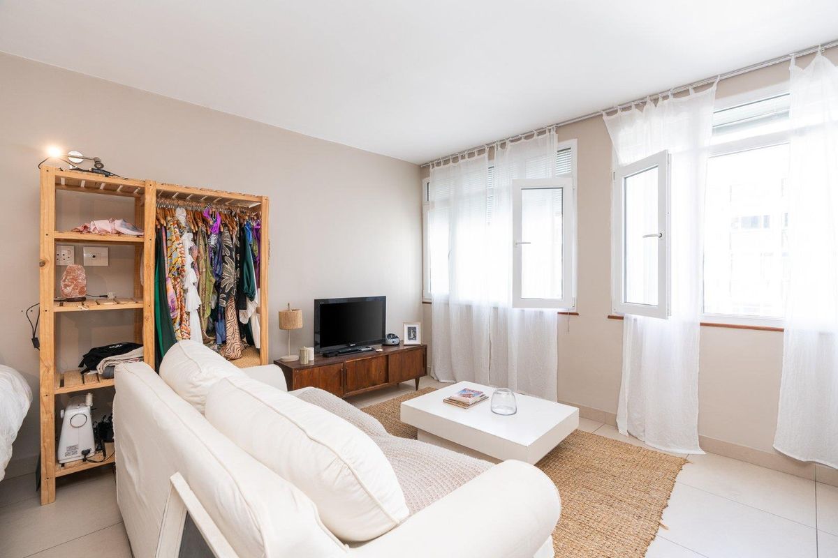 A bright living room featuring tiled flooring and large casement windows that allow for ample natural light.