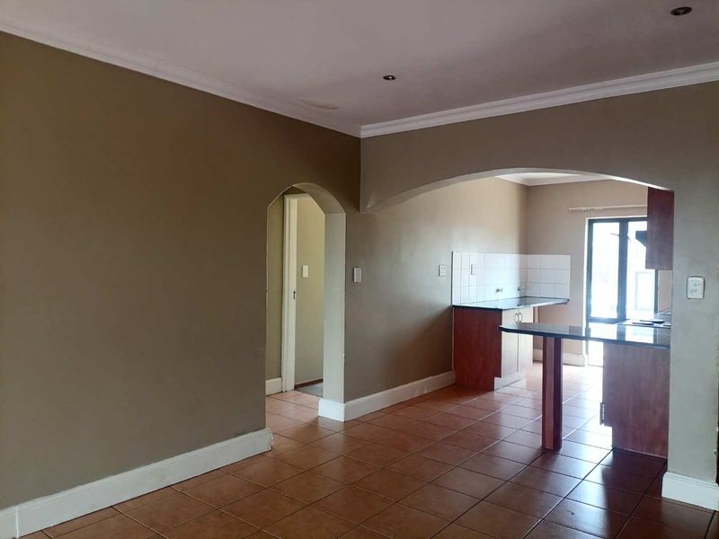 An open-plan living and kitchen area featuring tiled flooring, granite countertops, and arched architectural details, offering a functional layout ready for personalization.