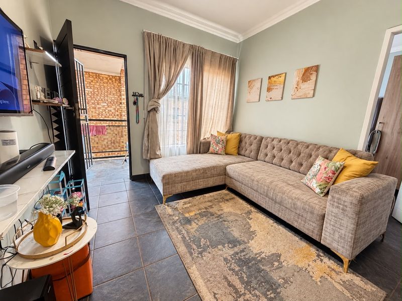 A comfortable living room featuring tiled flooring, decorative cornicing, and direct access to an outdoor balcony area.