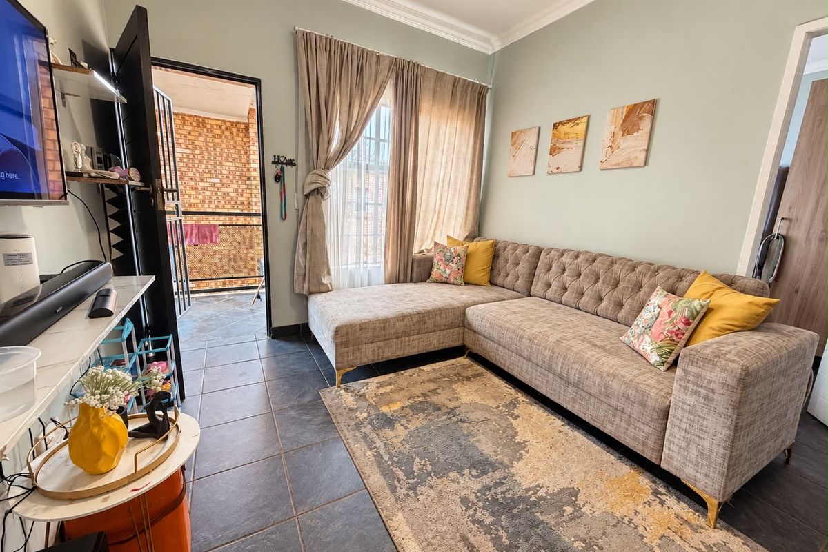 A comfortable living room featuring tiled flooring, decorative cornicing, and direct access to an outdoor balcony area.