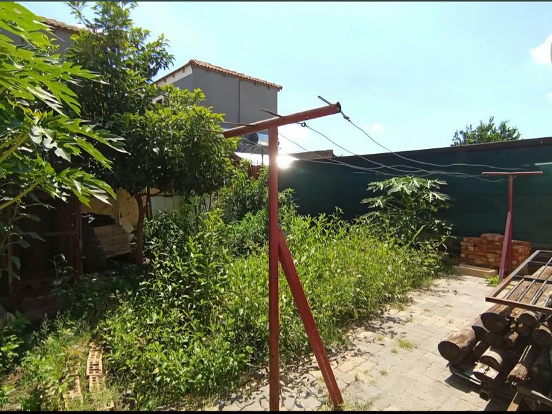 Rear garden area featuring a paved patio, metal washing line, and boundary fencing, currently requiring significant landscaping and maintenance.