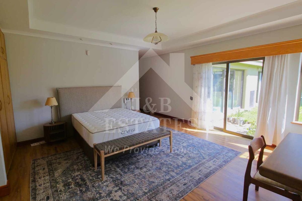 Spacious bedroom featuring built-in cupboards, tray ceiling, and large sliding glass doors providing direct access to the garden.