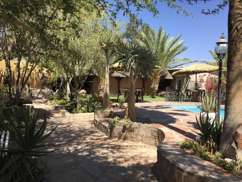 A landscaped outdoor pool area featuring stone paving, retaining walls, and mature trees, providing a tranquil setting for guests.