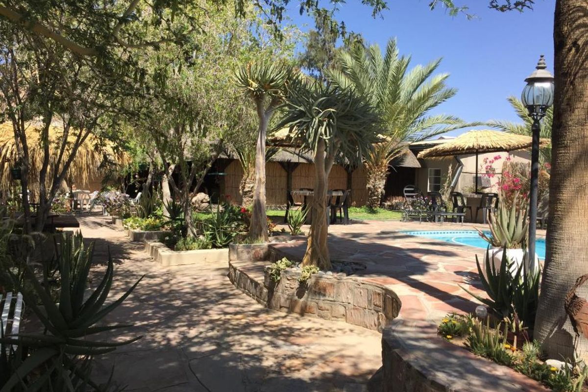 A landscaped outdoor pool area featuring stone paving, retaining walls, and mature trees, providing a tranquil setting for guests.