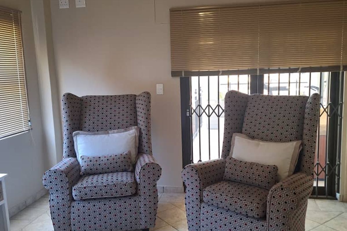 A living area featuring tiled flooring, venetian blinds, and security gates on the glass door leading to the exterior.