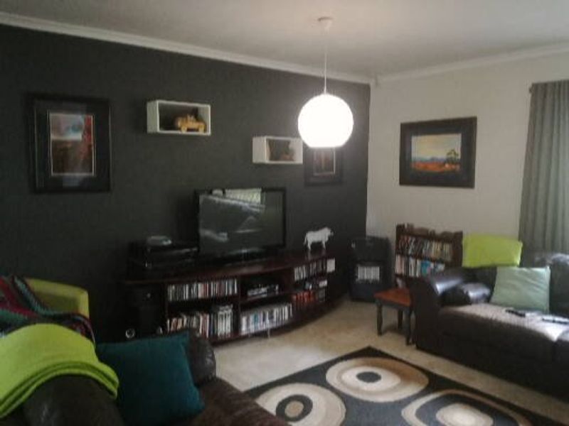 A living room featuring a dark accent wall, tiled flooring, and a central pendant light fixture.