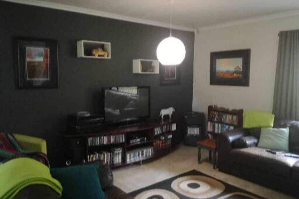 A living room featuring a dark accent wall, tiled flooring, and a central pendant light fixture.