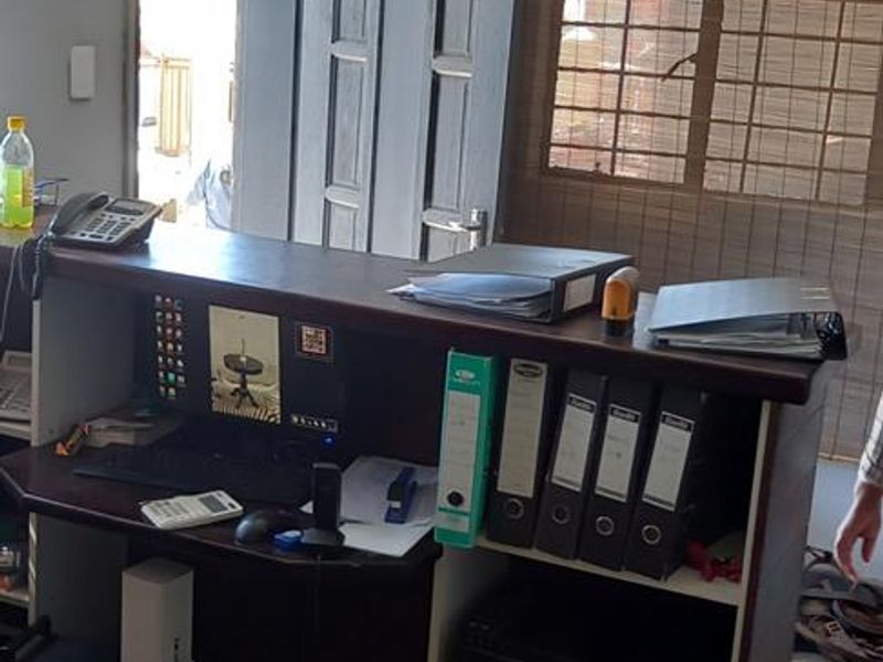 A functional office space featuring tiled flooring, security window bars, and a built-in reception desk area.