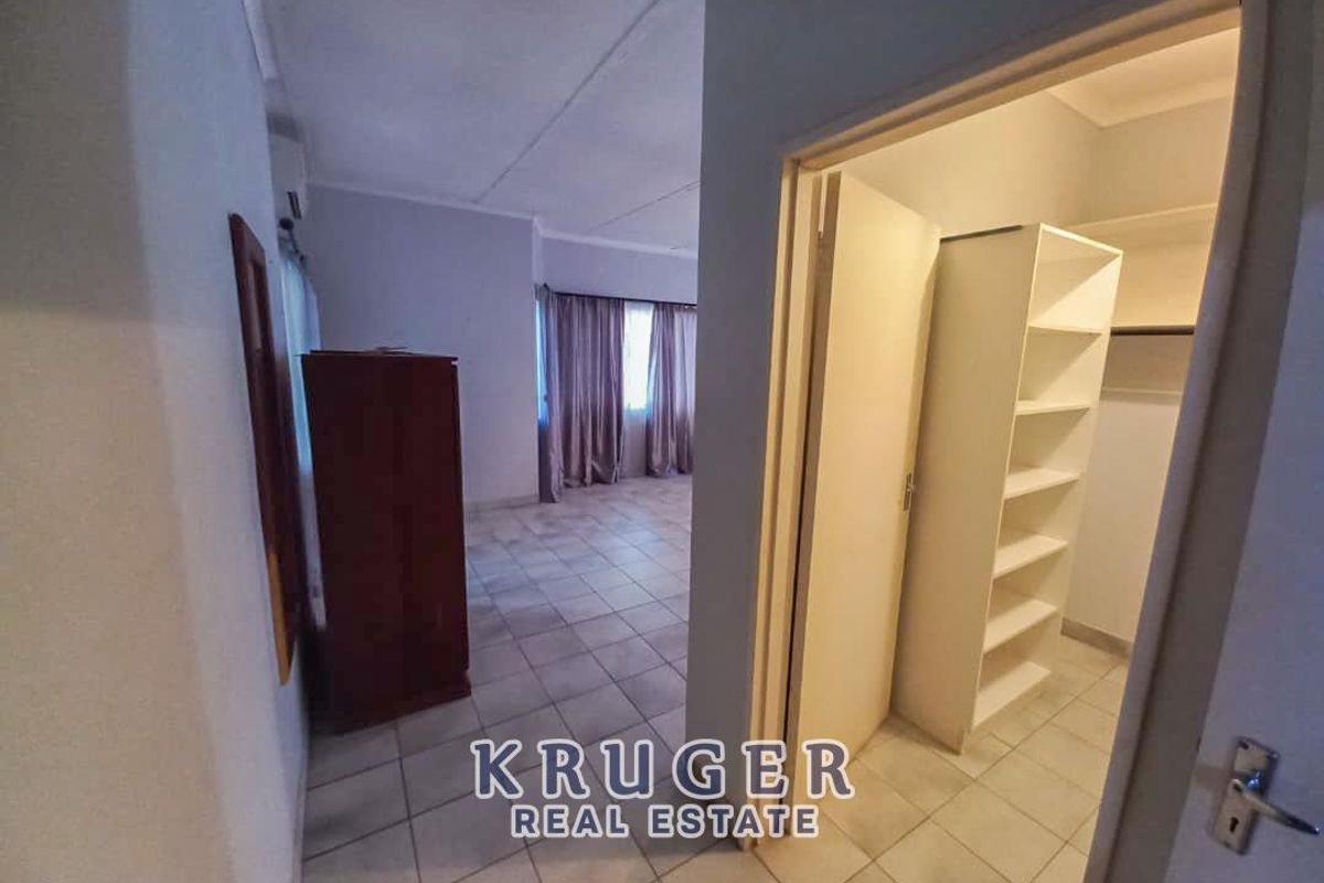 A bedroom featuring tiled flooring and an adjacent walk-in closet with built-in shelving.