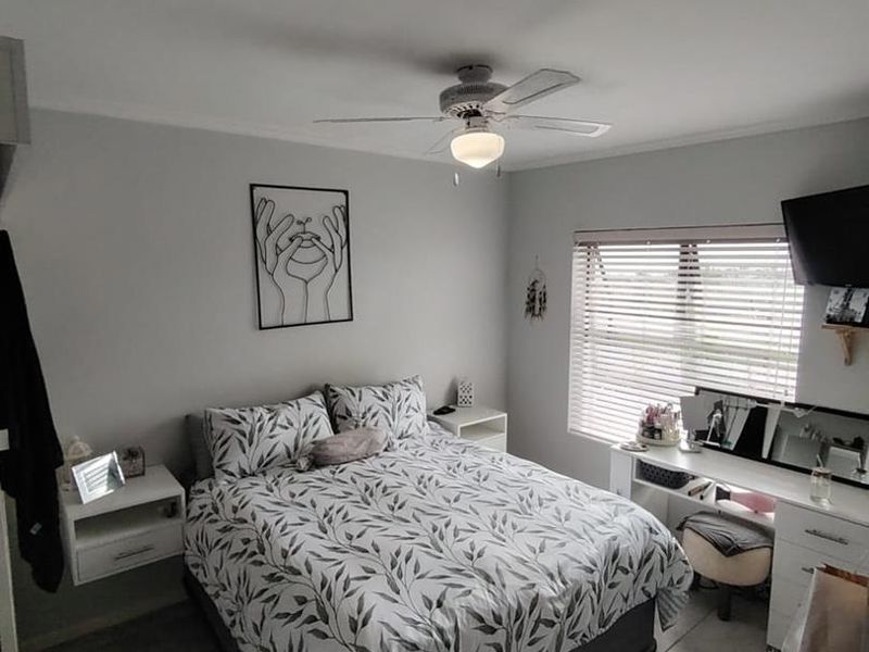 A well-maintained bedroom featuring tiled flooring, a central ceiling fan, and venetian blinds, providing a clean and functional living space.