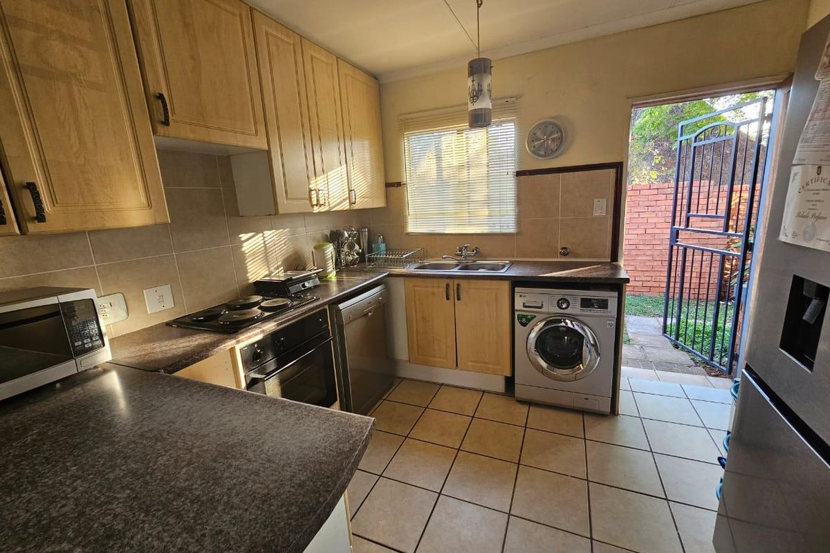 Functional kitchen featuring laminate cabinetry, built-in oven, electric hob, and tiled flooring with direct access to the rear exterior area.