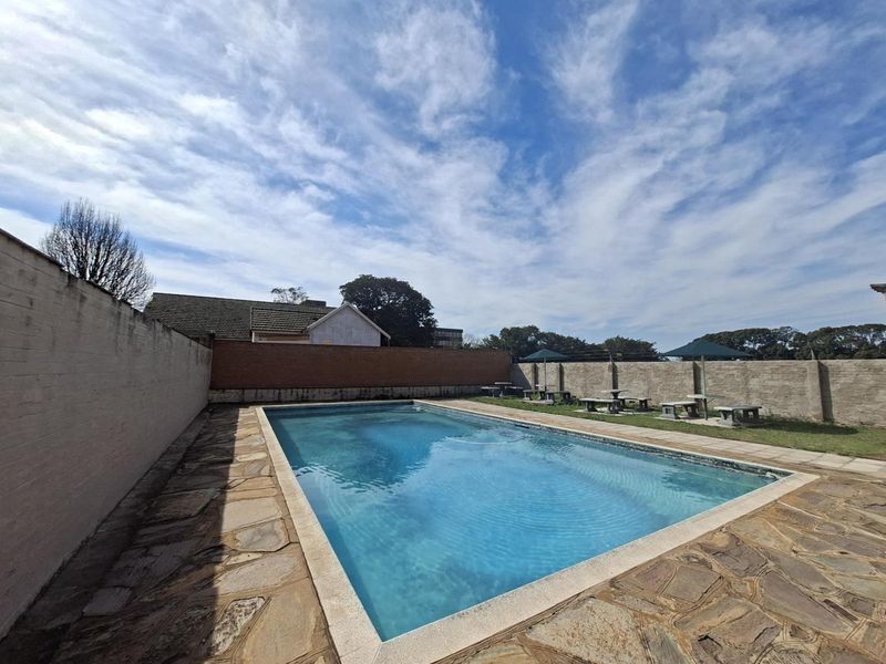 Outdoor swimming pool area featuring stone paving and perimeter walling, providing a private recreational space.