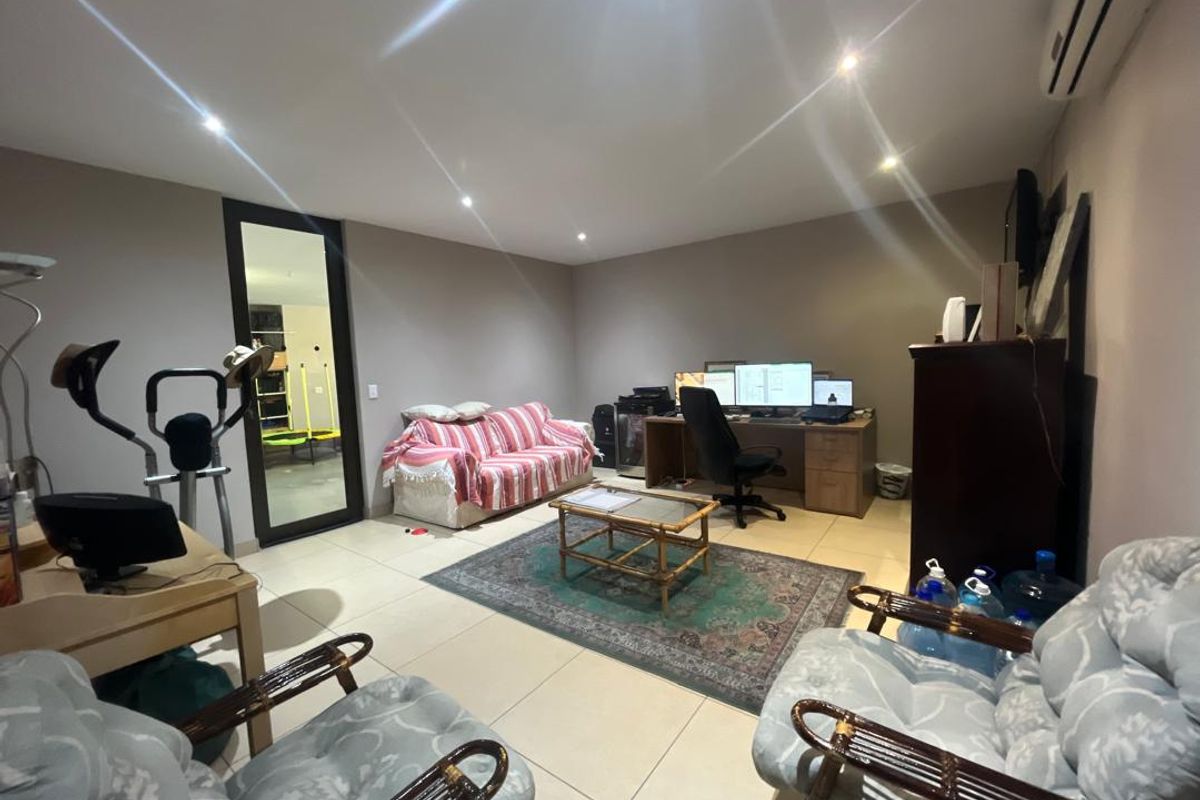 A multi-purpose living area featuring tiled flooring, recessed downlighting, and a wall-mounted split-system air conditioner.