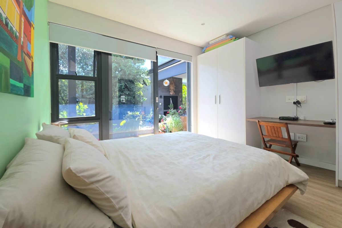 A bright bedroom featuring built-in cabinetry, a wall-mounted desk, and large sliding glass doors providing direct access to the outdoor patio area.