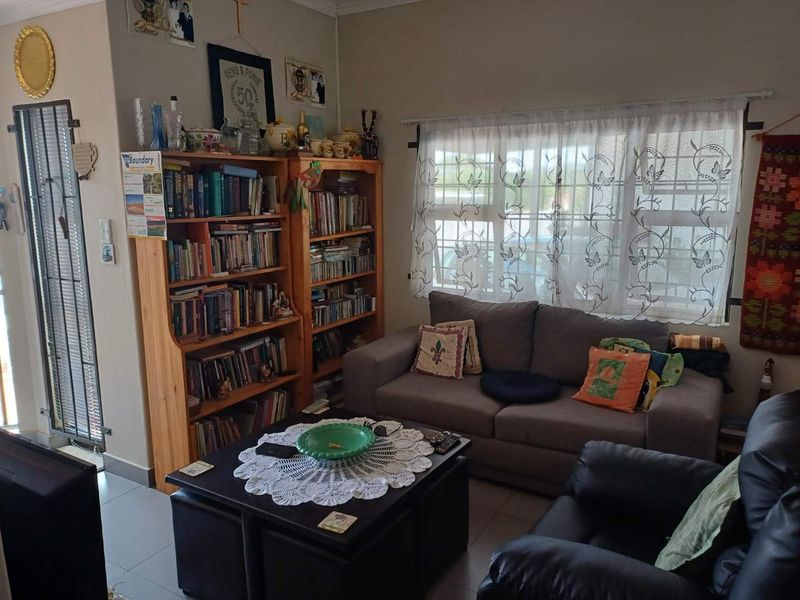 A cozy living room featuring tiled flooring, a window with security bars, and a security gate entrance.