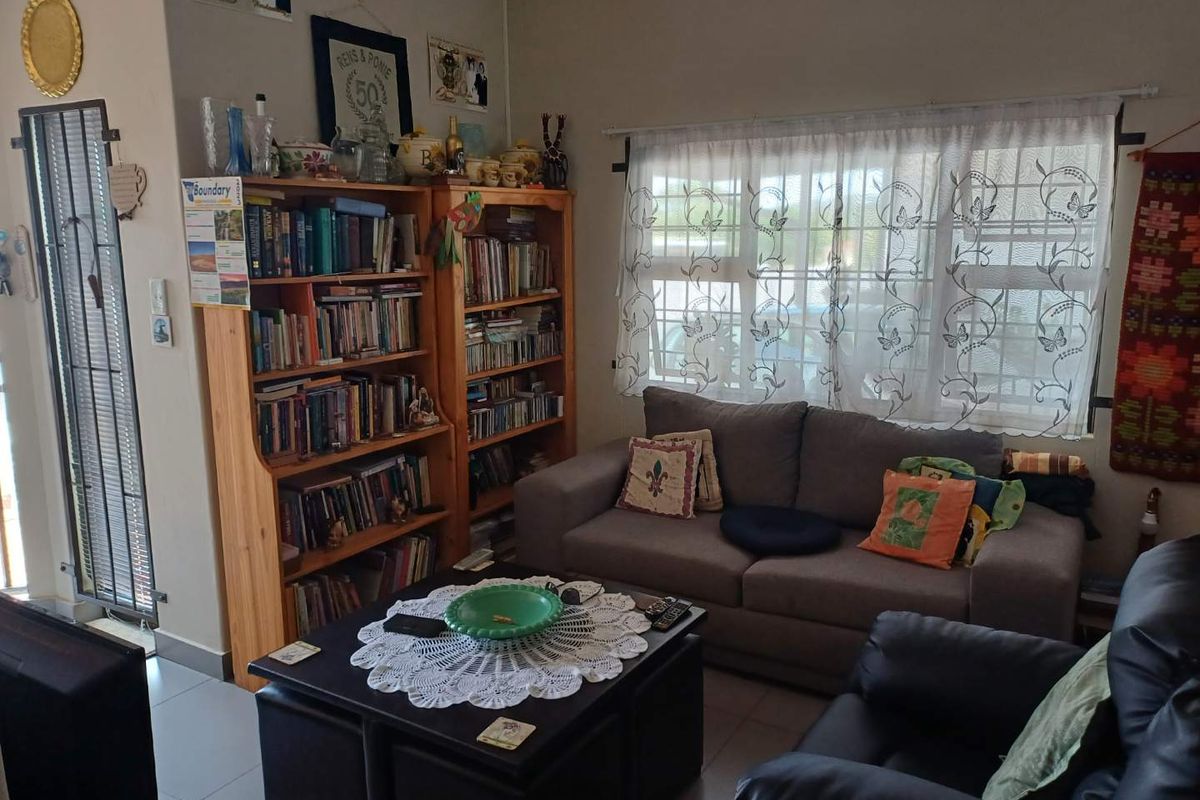 A cozy living room featuring tiled flooring, a window with security bars, and a security gate entrance.