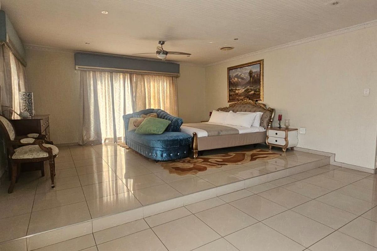Spacious bedroom featuring a raised platform area, tiled flooring, ceiling fan, and sliding glass doors leading to an outdoor space.