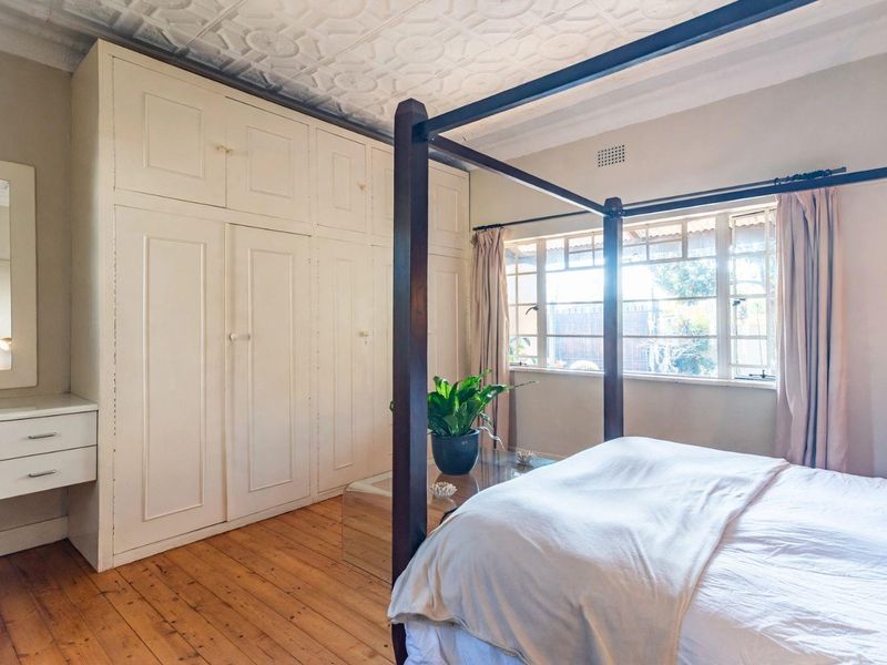 A well-maintained bedroom featuring original timber flooring, a decorative pressed metal ceiling, and extensive built-in cabinetry for storage.