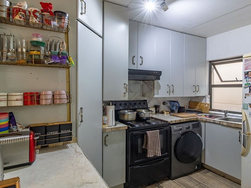 Compact kitchen featuring built-in cabinetry, laminate countertops, a stainless steel sink, and tiled flooring, offering a functional layout for daily meal preparation.