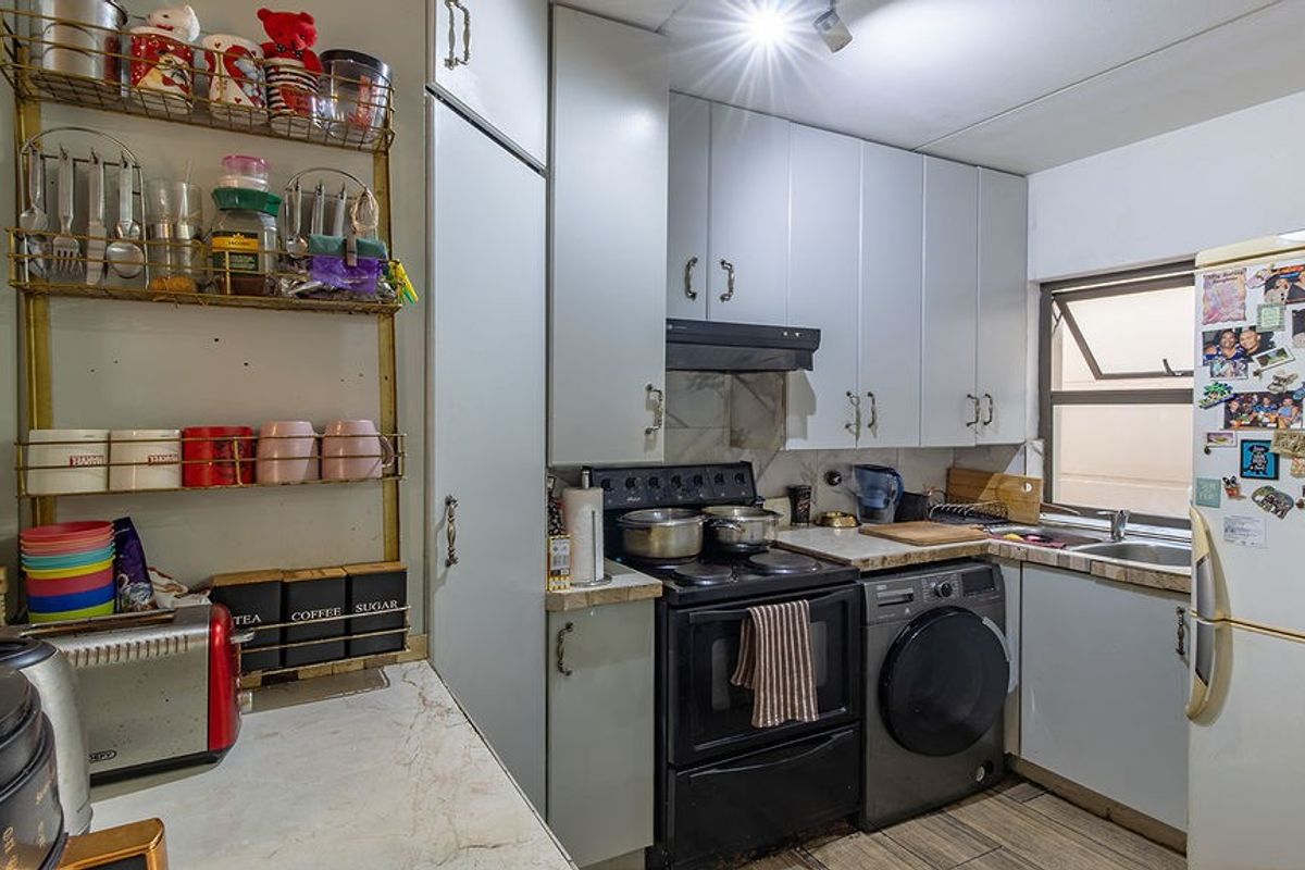 Compact kitchen featuring built-in cabinetry, laminate countertops, a stainless steel sink, and tiled flooring, offering a functional layout for daily meal preparation.