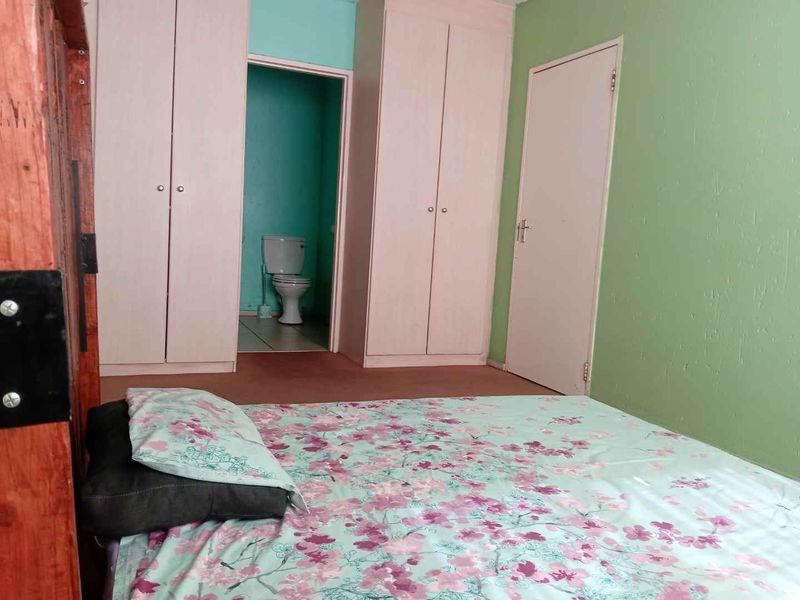 Bedroom featuring built-in cupboards and an attached en-suite bathroom with a toilet.