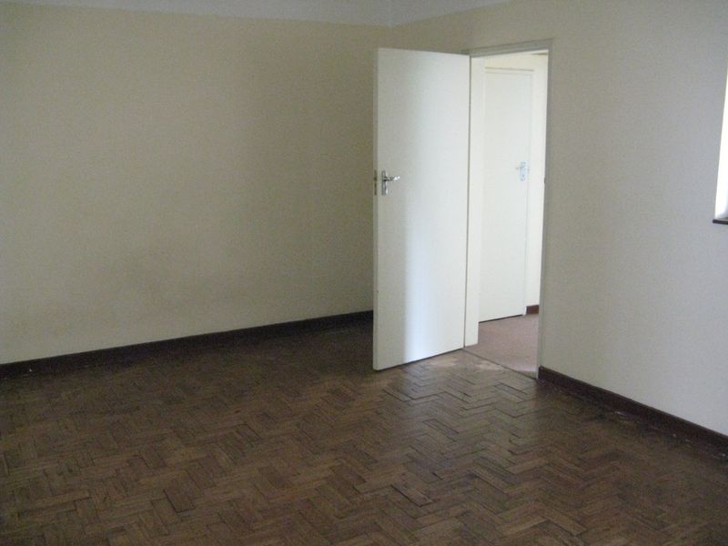 An empty bedroom featuring traditional parquet flooring and neutral wall finishes, providing a blank canvas for potential interior design updates.
