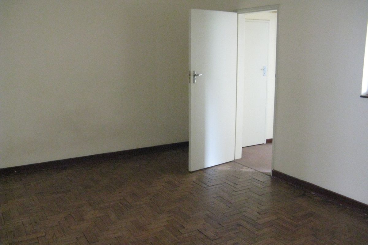 An empty bedroom featuring traditional parquet flooring and neutral wall finishes, providing a blank canvas for potential interior design updates.
