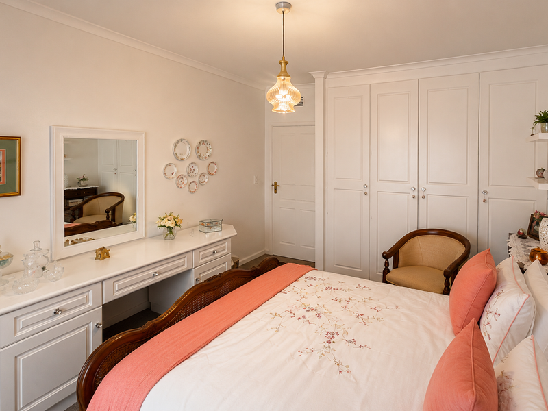 A well-maintained bedroom featuring extensive built-in cabinetry, a matching vanity unit, and elegant coving detail.