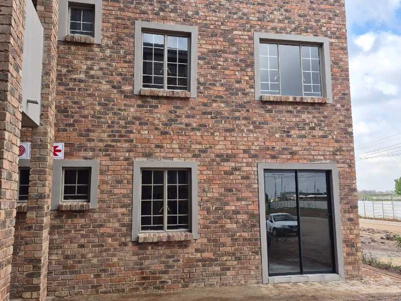 Exterior view of a multi-story apartment building featuring a face brick facade, aluminium windows, and a paved ground-level entrance area.
