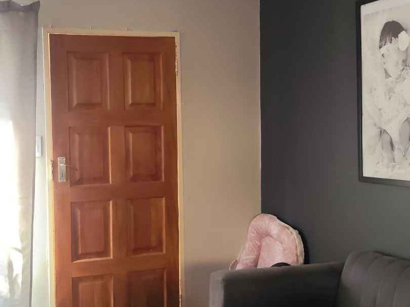 A living room area featuring a traditional timber panel door and carpeted flooring, with a dark accent wall.