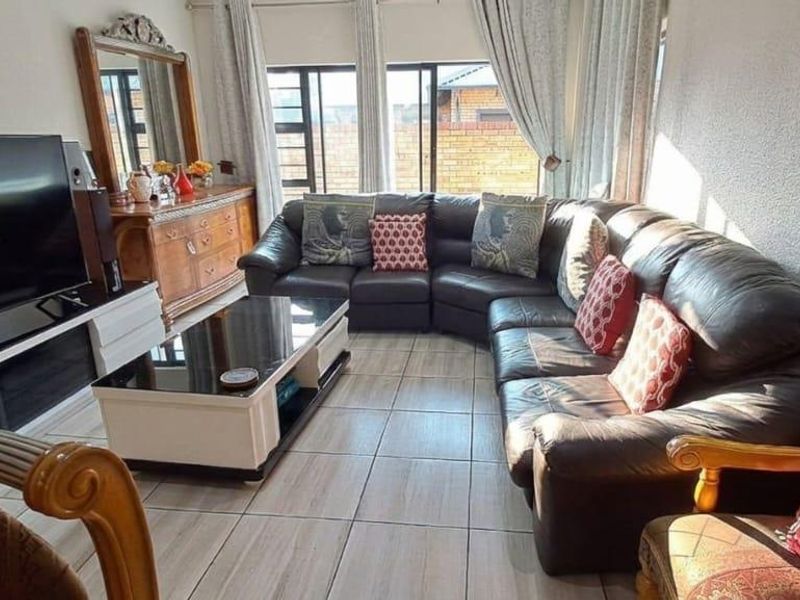 A comfortable living room featuring tiled flooring and large windows that provide natural light, creating a bright and inviting space.