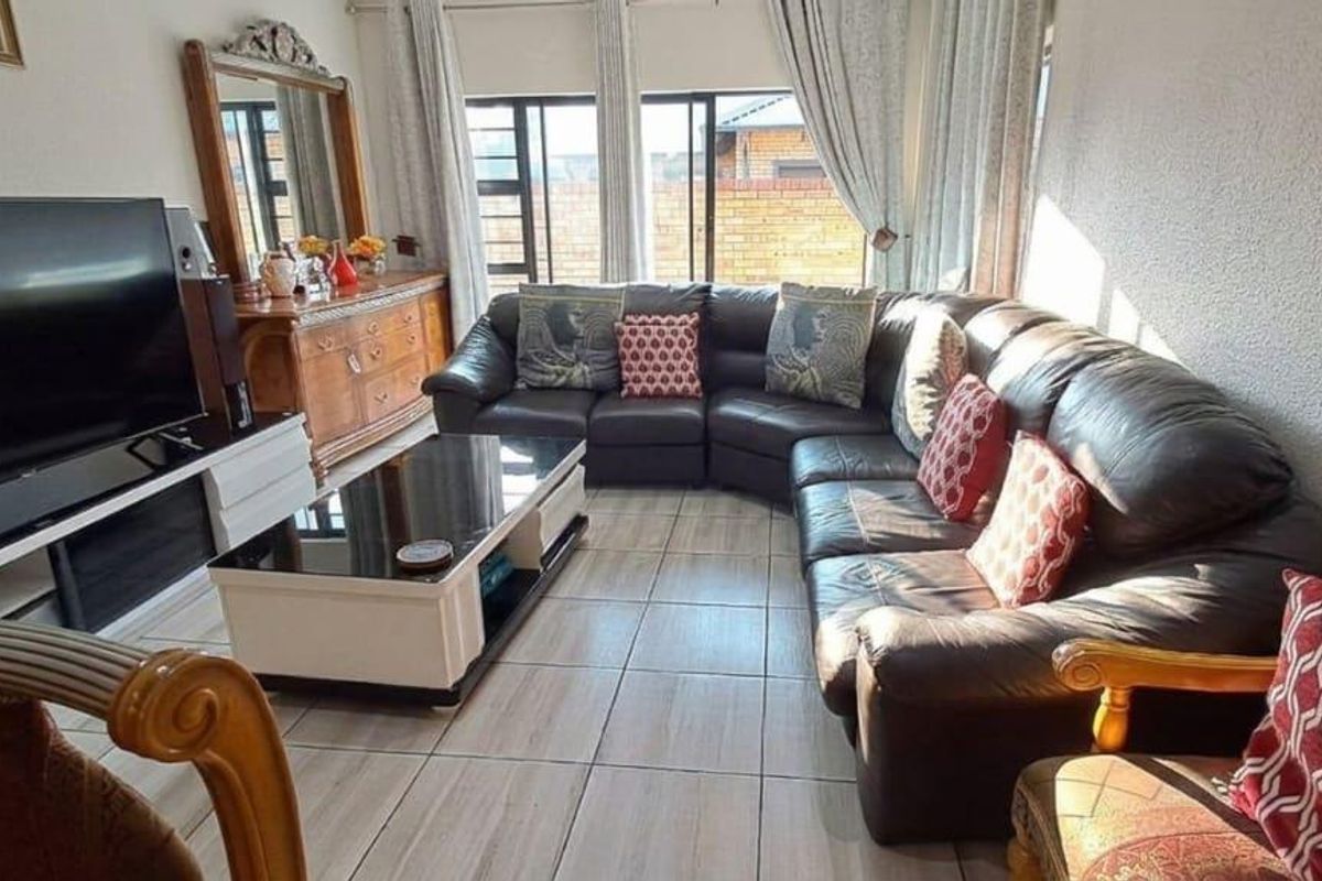 A comfortable living room featuring tiled flooring and large windows that provide natural light, creating a bright and inviting space.