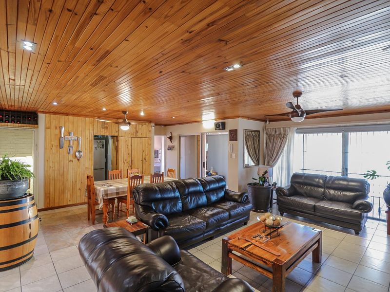 Spacious open-plan living and dining area featuring a distinctive timber-clad ceiling, tiled flooring, and large sliding doors providing natural light.