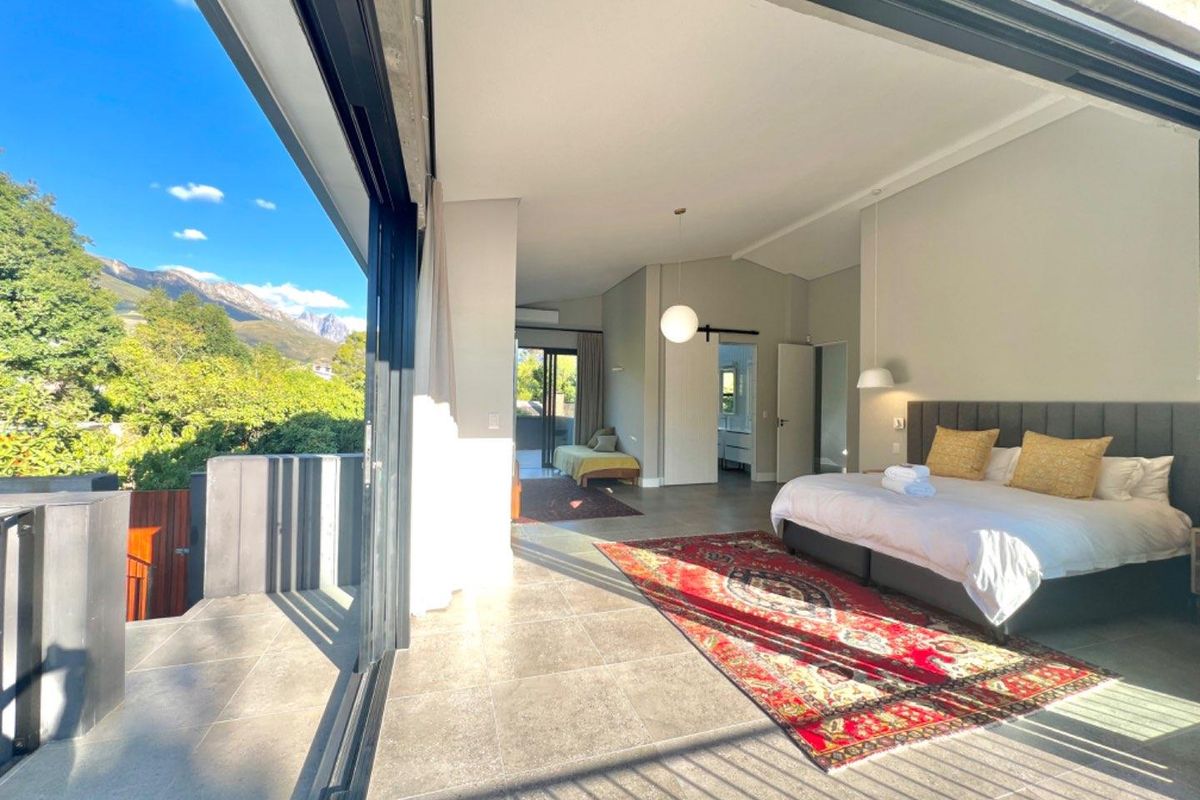 Spacious bedroom featuring large sliding glass doors that open onto a private balcony with scenic mountain views and tiled flooring throughout.