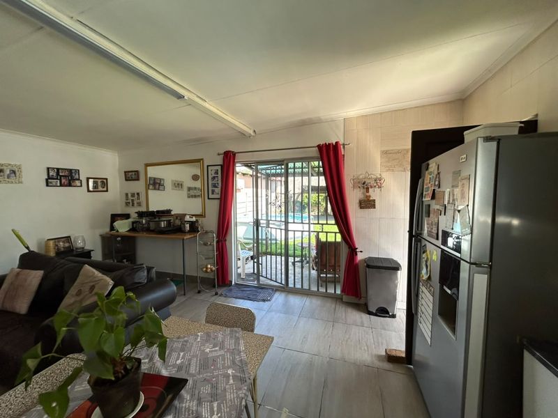 Open plan living area featuring tiled flooring and a sliding glass door providing direct access to the rear patio and pool area.