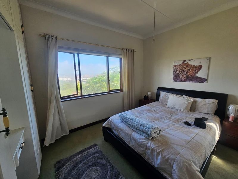 A bedroom featuring a built-in cupboard, ceiling fan, and a window with views, offering a functional space ready for cosmetic updates.
