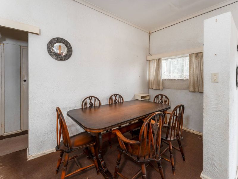 A dining area featuring textured walls and carpet flooring, offering a functional space that could benefit from modern updates to finishes and lighting.
